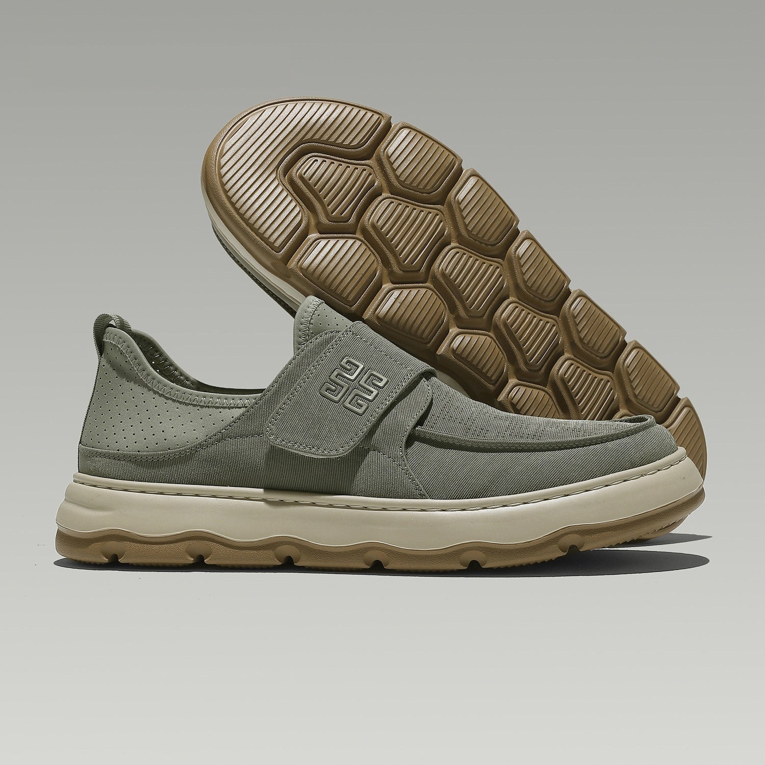 Green slip-on shoe with brown sole on a gray background