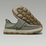 Green slip-on shoe with brown sole on a gray background