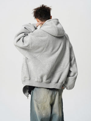 Person wearing a gray hoodie and light blue jeans on a white background