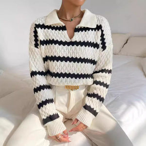 Person wearing a white and black striped sweater with a neutral background