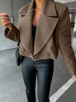 Person wearing a brown coat and black pants in an urban setting