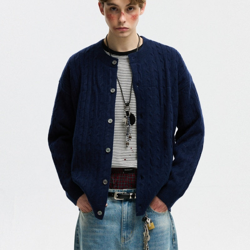 Person wearing a navy blue cardigan over a striped shirt with a plain background