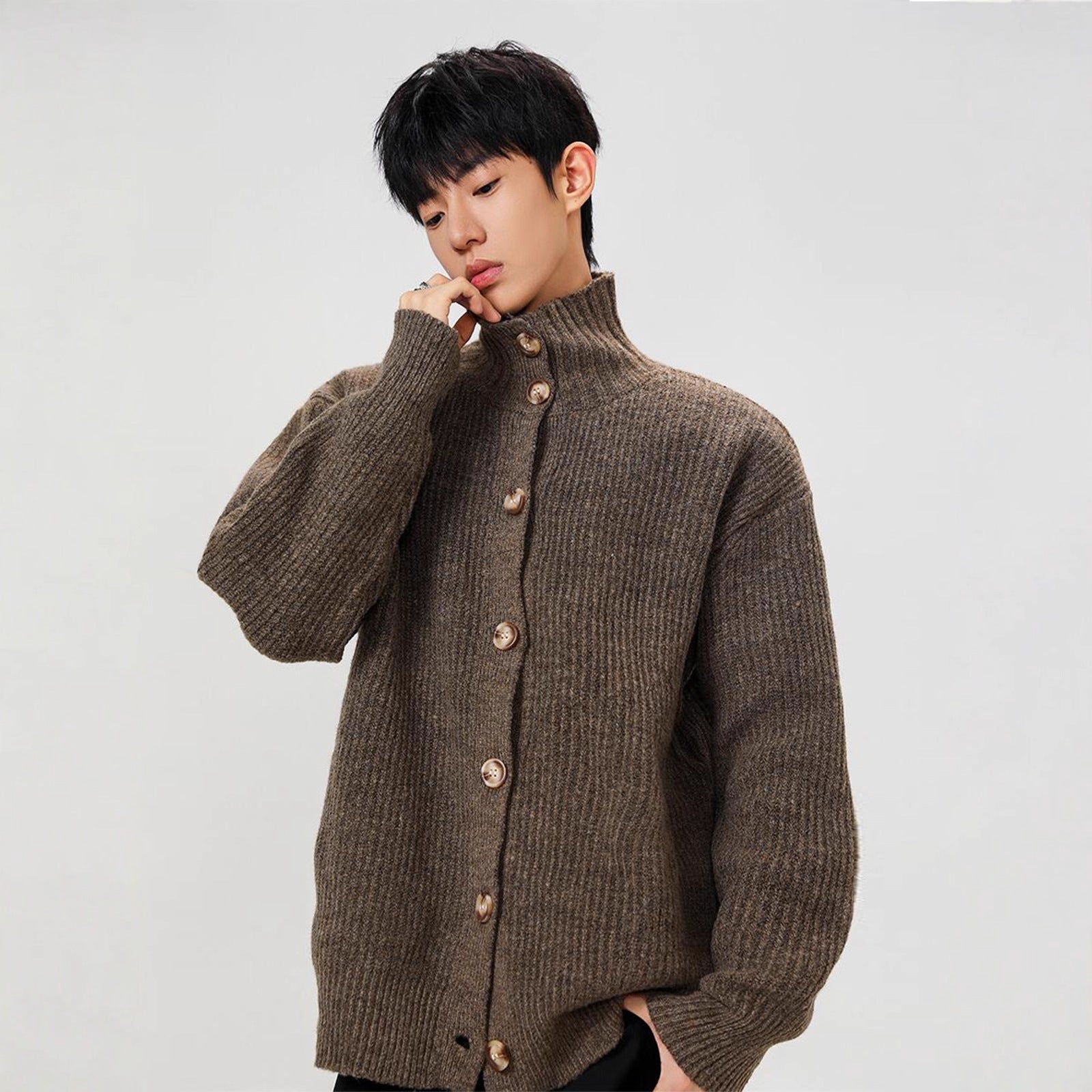 Person wearing a brown knitted cardigan on a plain background