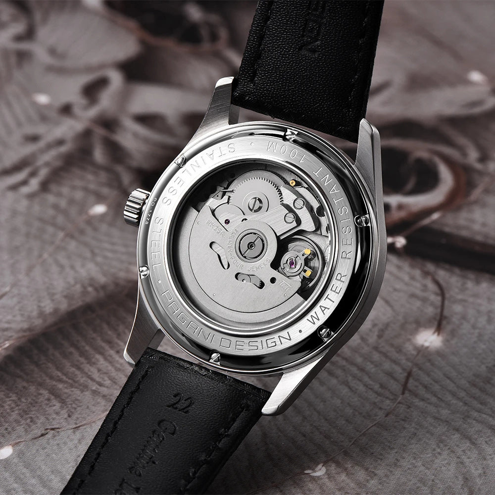 Watch with black leather strap and visible mechanical components on a textured surface
