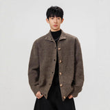 Person wearing a brown textured jacket on a plain background