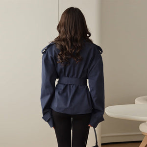 Person wearing a navy blue jacket in a minimal indoor setting