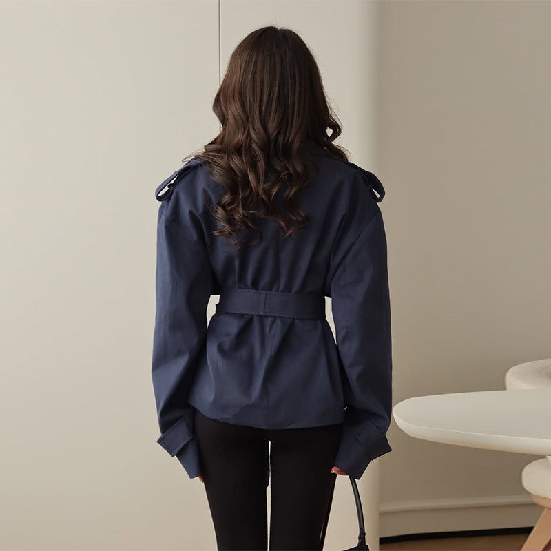 Person wearing a navy blue jacket in a minimal indoor setting