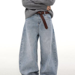 Light blue jeans worn with a gray sweater and brown belt on a white background
