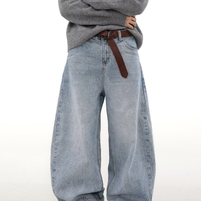 Light blue jeans worn with a gray sweater and brown belt on a white background