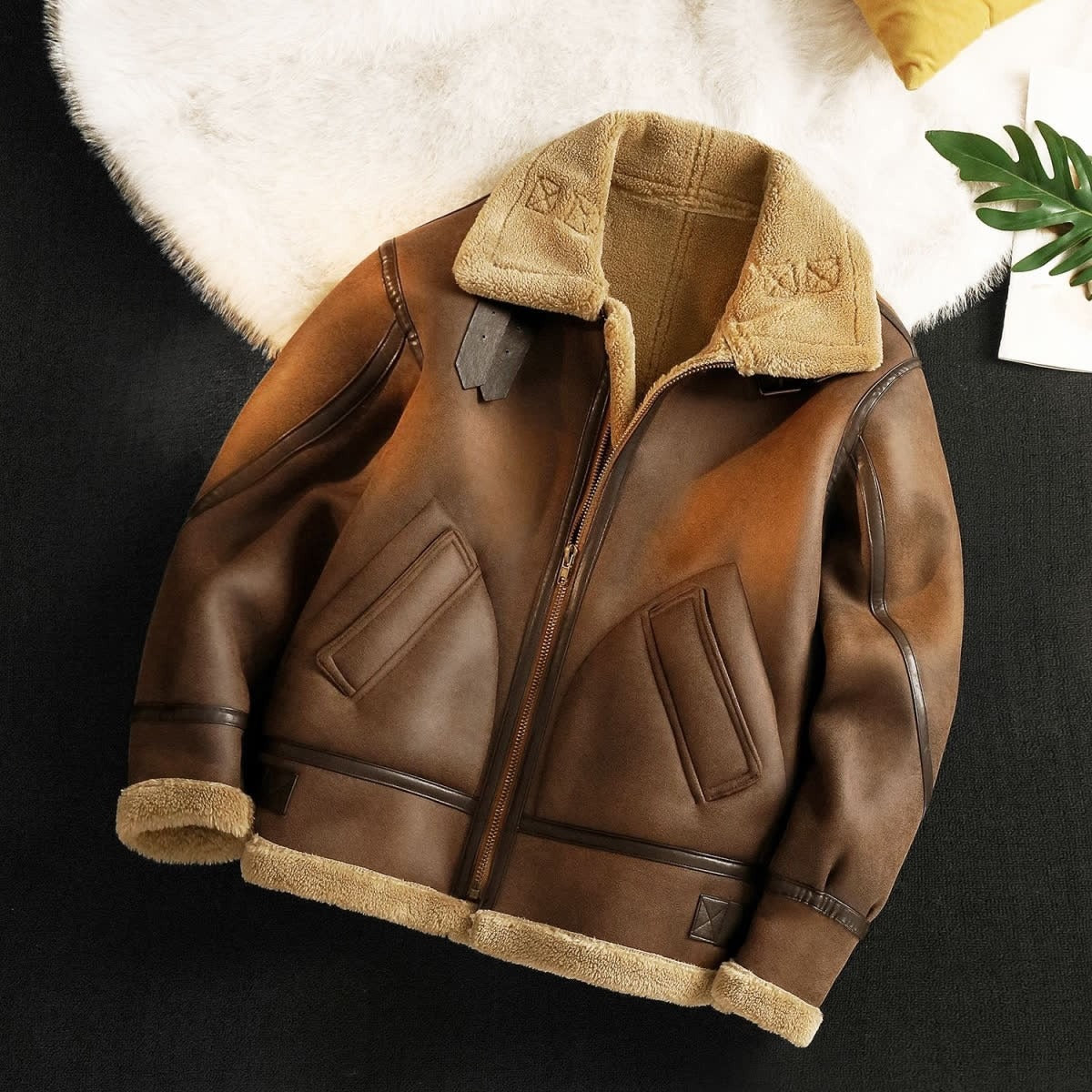 Brown leather jacket with beige fur lining on a dark surface