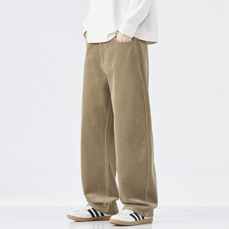 Person wearing beige corduroy pants with a white shirt and Adidas shoes on a white background