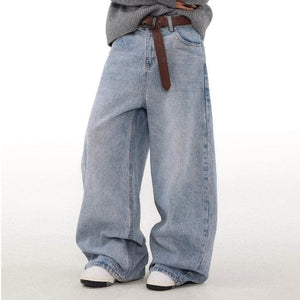 Person wearing oversized light blue jeans with a brown belt on a white background