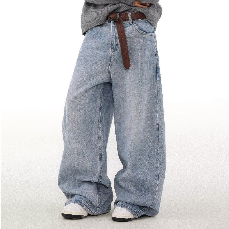 Person wearing oversized light blue jeans with a brown belt on a white background