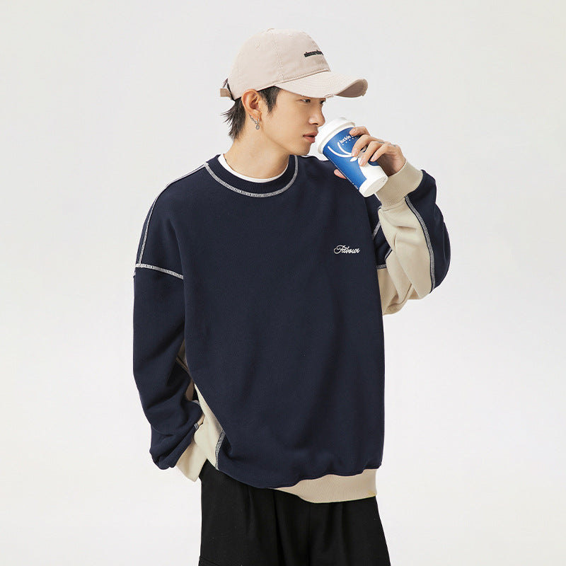 Person wearing a navy sweatshirt with a brand logo, holding a blue cup against a white background