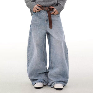 Person wearing wide-leg jeans with a brown belt on a white background