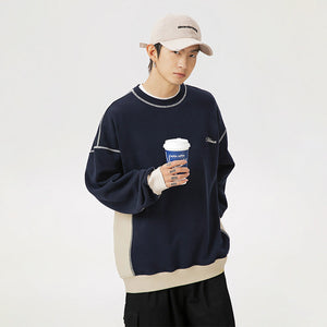Person wearing a navy sweater with white accents, holding a coffee cup against a plain background