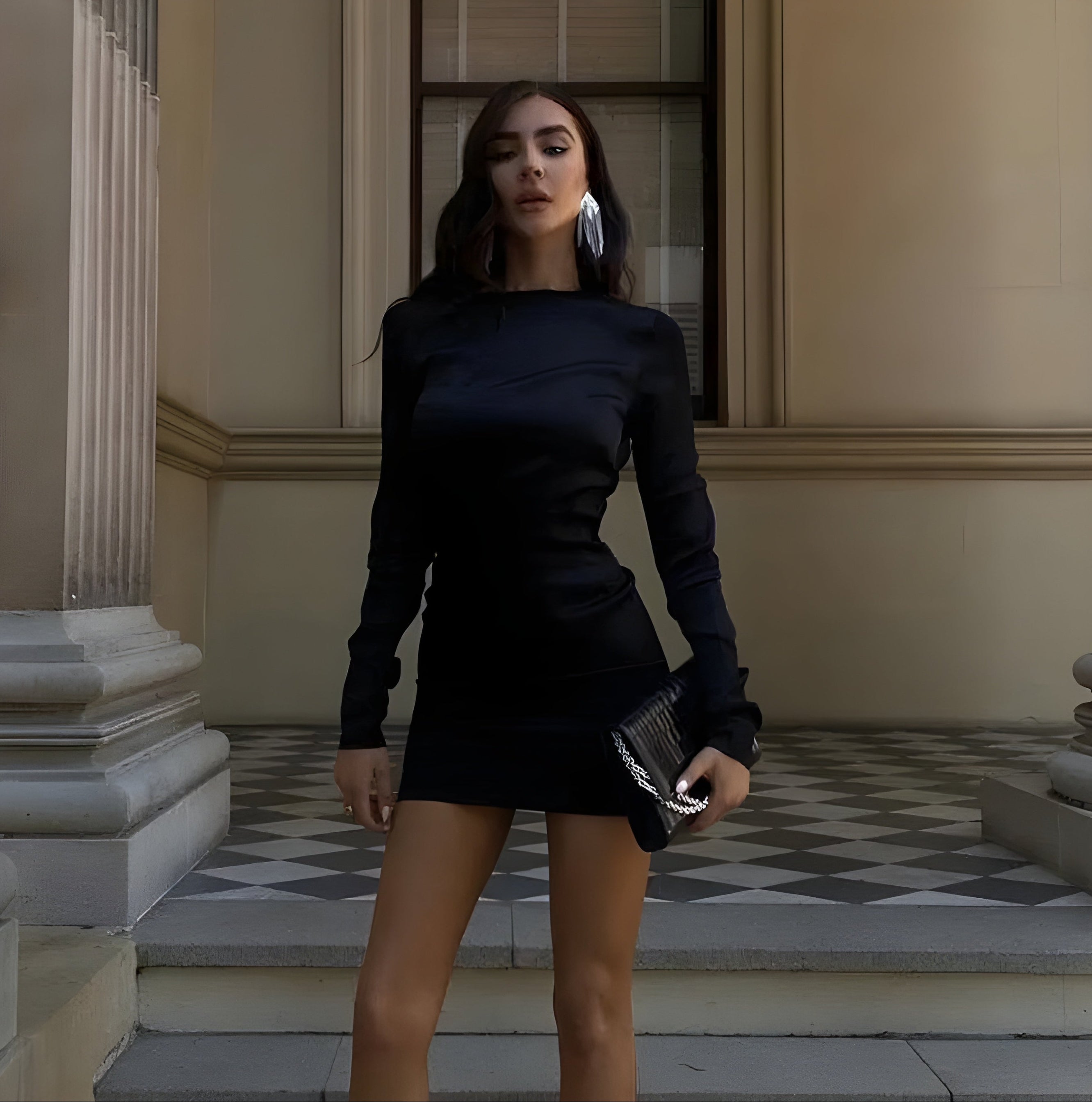 Woman in a black dress standing on steps in front of a building