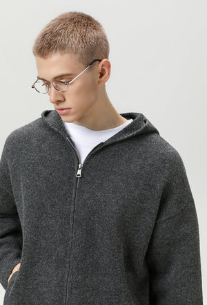 Person wearing a gray zip-up hoodie and glasses on a plain background