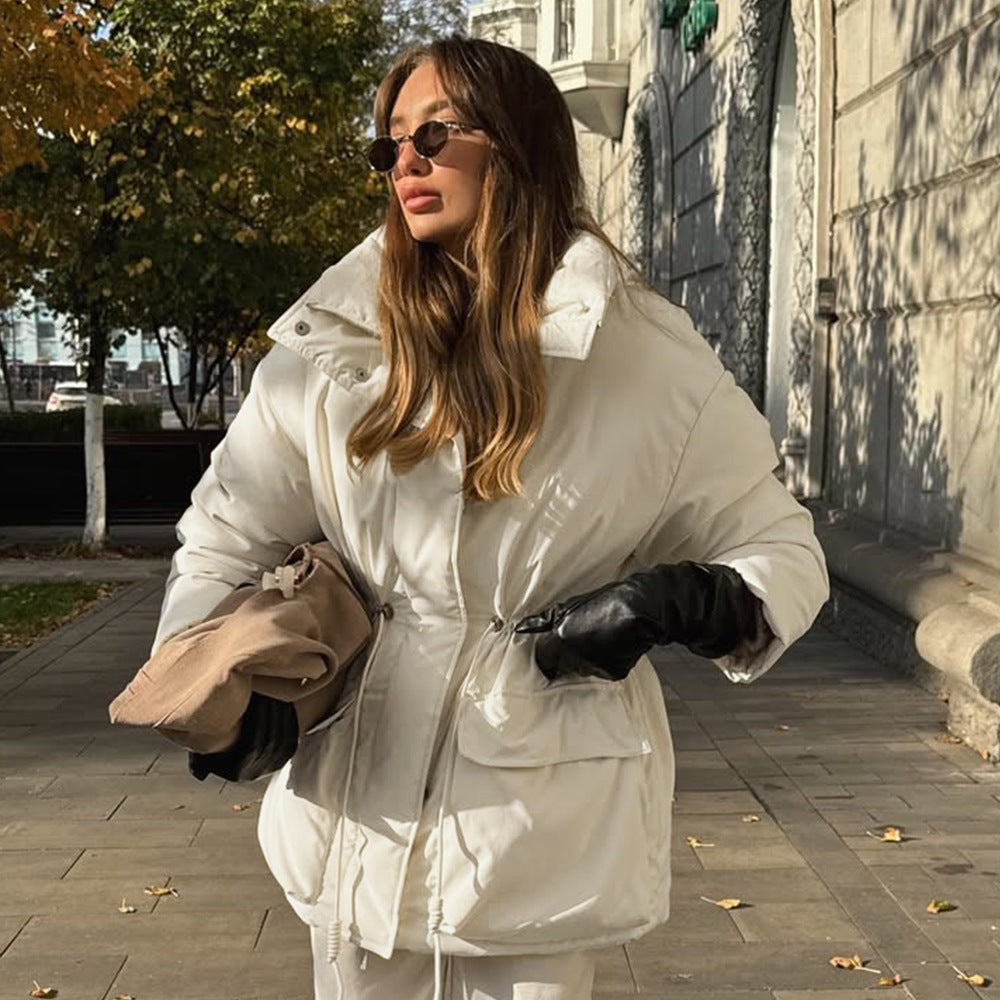 Woman wearing a white puffer jacket on a city street.