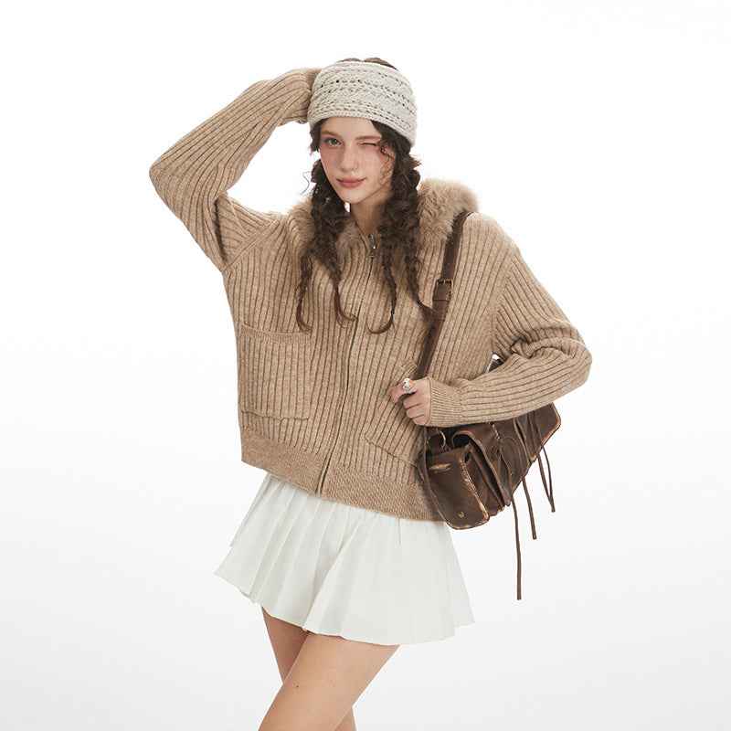 Woman wearing a beige sweater and white skirt with a brown bag on a white background