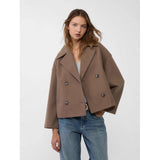 Woman wearing a brown coat and blue jeans on a white background