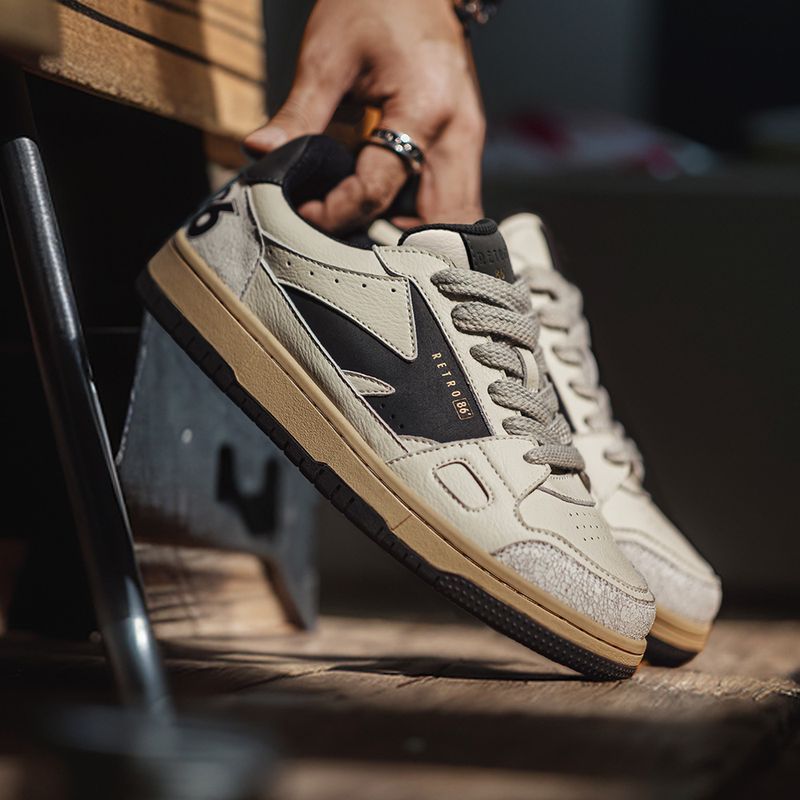 Beige sneakers with black accents on a wooden floor.