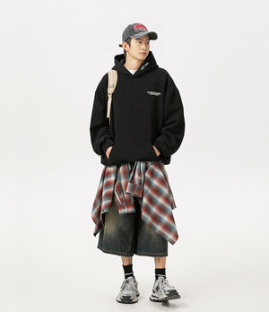 Person wearing a black hoodie, plaid skirt, and sneakers on a white background
