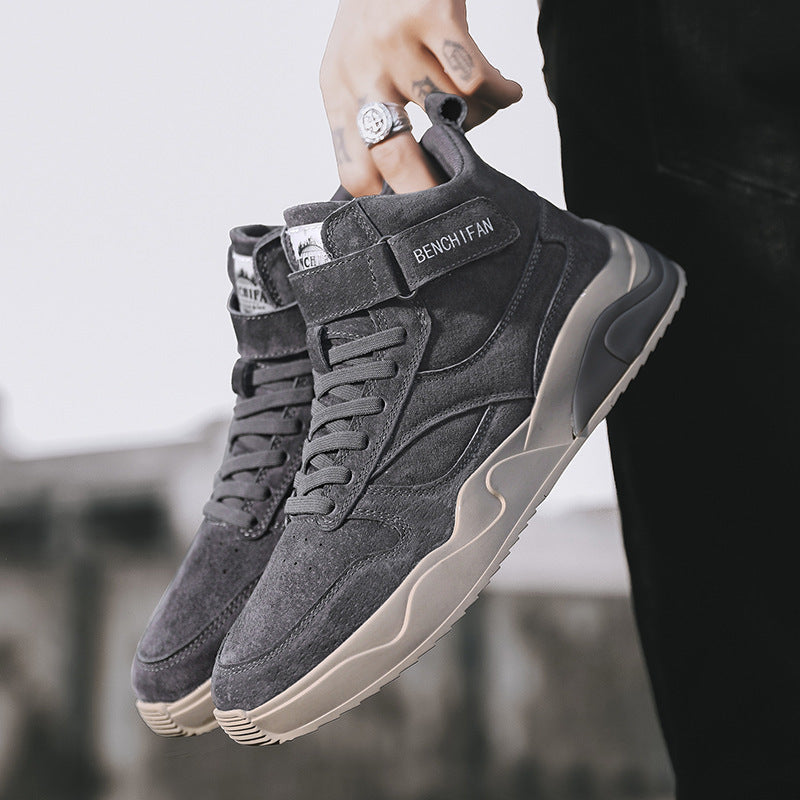 Gray high-top sneakers held by a person with a blurred background